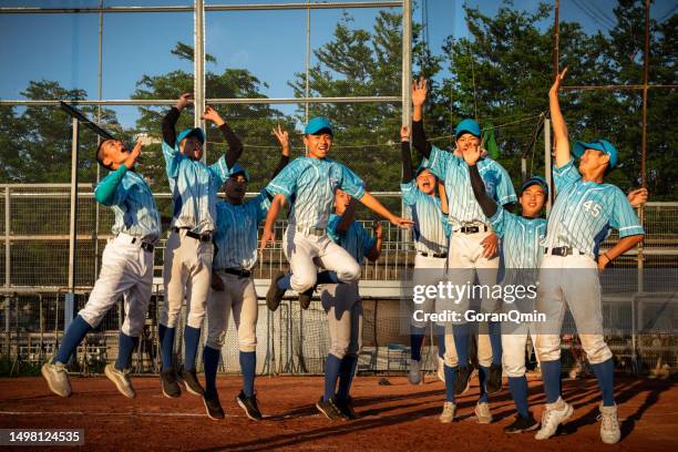 wide shot of baseball team celebrating by jumping up to the air on the mound after winning professional baseball game at the end of regular season in stadium - match final stock pictures, royalty-free photos & images