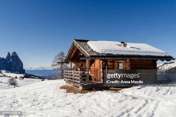 a wooden mountain hut in the snowy landscape of seiser alm - alphütte stock-fotos und bilder