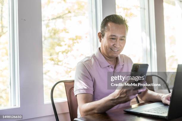 man using laptop at dining room table - filipino people stock pictures, royalty-free photos & images