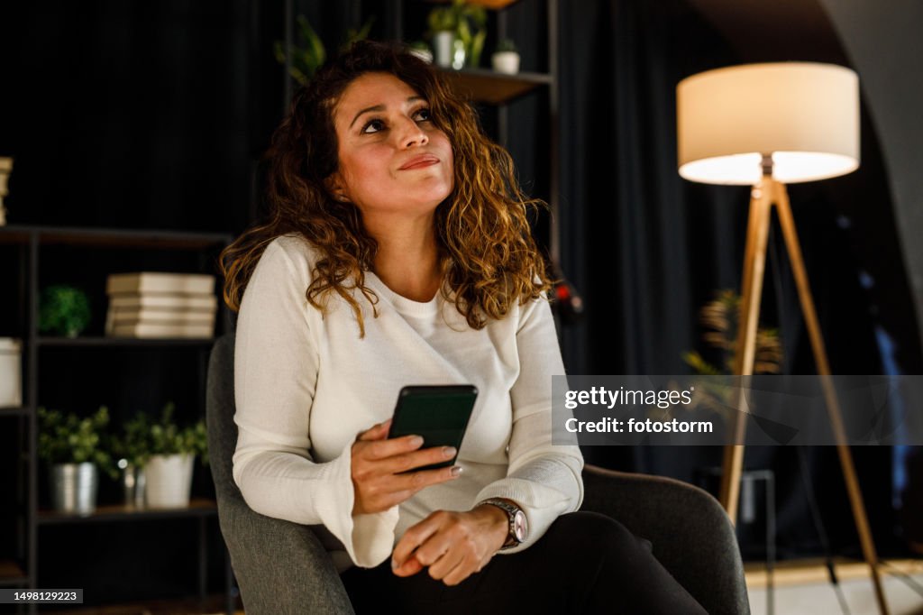 Frau, die aufschaut und überlegt, was sie auf eine Textnachricht antworten soll