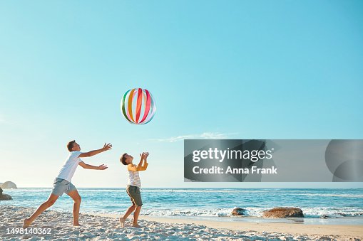Hermanos jugando con una pelota en la playa Hermanos jugando con una pelota en la playa