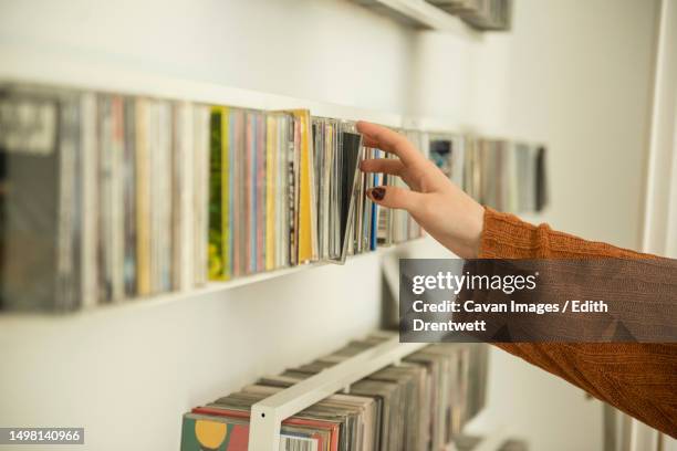 close-up of a woman hand picking a cd from shelf, munich, bavaria, germany - colored cds stock pictures, royalty-free photos & images