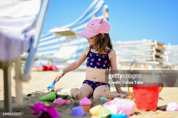 child playing with beach toys on a sandy beach. - 2 girls 1 sandbox stock pictures, royalty-free photos & images