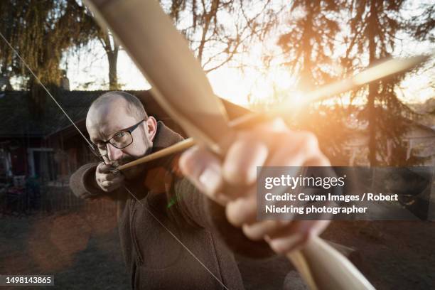 male archer aiming arrow, bavaria, germany - bogen pfeil und bogen stock-fotos und bilder