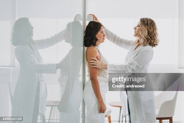 woman measuring height at doctor's office - lengte stockfoto's en -beelden