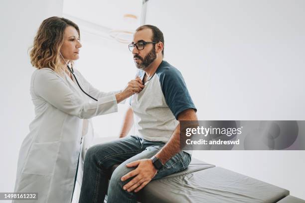 doctora mujer escuchando los latidos del corazón - corazón humano fotografías e imágenes de stock
