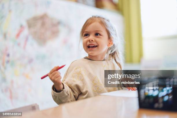 kleines mädchen zeichnet mit markern im kindergarten - kindheit stock-fotos und bilder