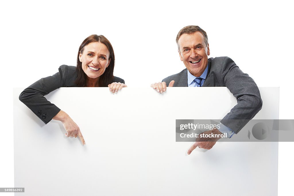 Mature couple isolated on white background pointing at board
