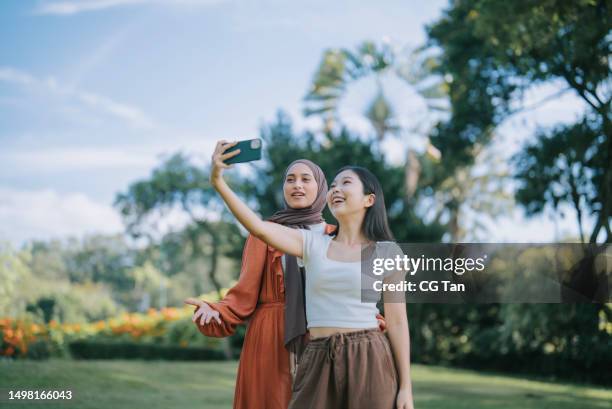 asian group friends selfie at public park in weekend morning with smart phone - malay people stock pictures, royalty-free photos & images