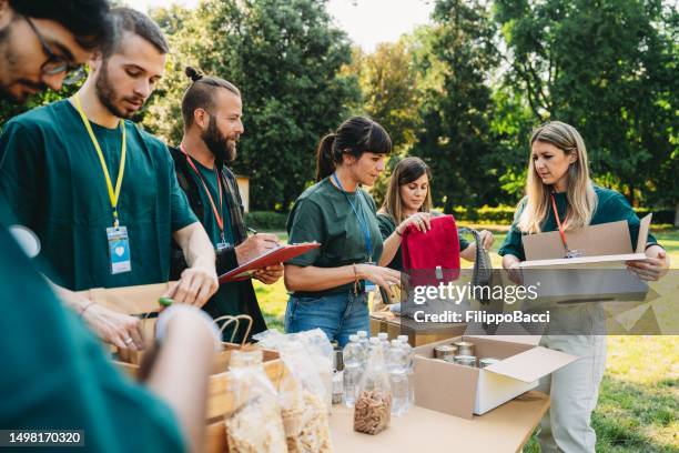 i volontari lavorano insieme al banco del cibo e dei vestiti - aiuti umanitari foto e immagini stock