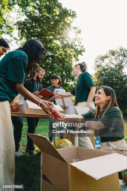 un groupe de personnes travaille ensemble dans une banque de nourriture et de vêtements - fondation caritative photos et images de collection