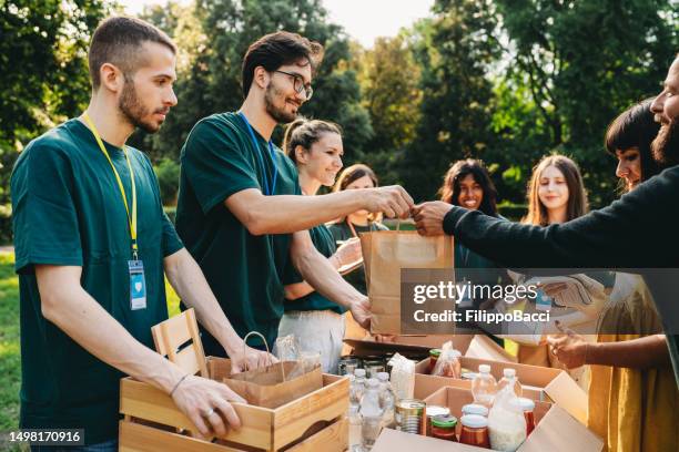 una coppia sta prendendo un sacchetto di cibo alla banca del cibo e dei vestiti - relief foto e immagini stock