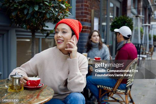 young woman using smart phone at cafe - beige trousers stock pictures, royalty-free photos & images