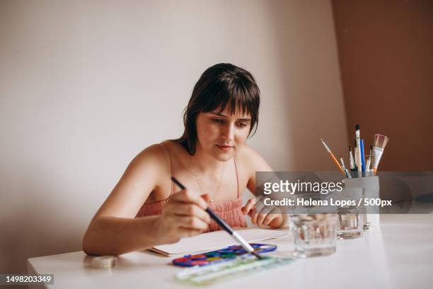 portrait of a young woman painting on paper at table at home,belo horizonte,state of minas gerais,brazil - aquarela stock pictures, royalty-free photos & images