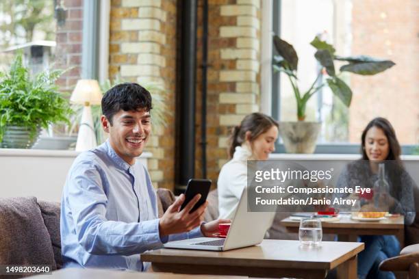 mid adult man using smart phone in cafe - busy coffee shop stock pictures, royalty-free photos & images
