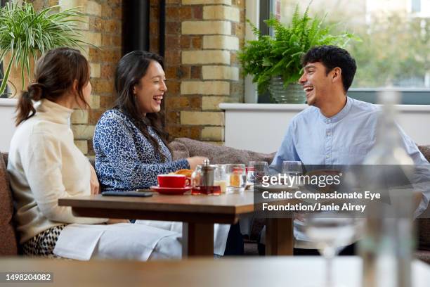 three relaxed business colleagues having business meeting in café - restuarant stock pictures, royalty-free photos & images