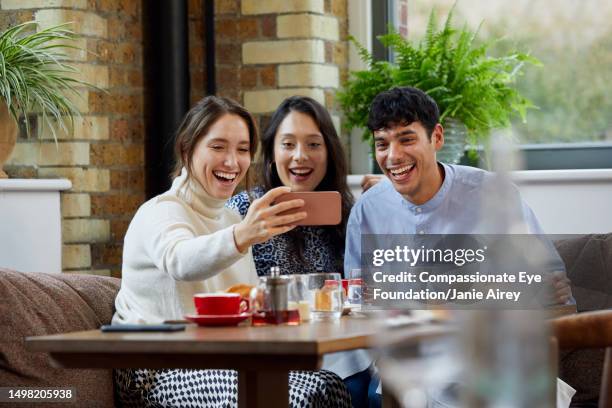 group of friends using phone in cafe - man eye cream stock pictures, royalty-free photos & images