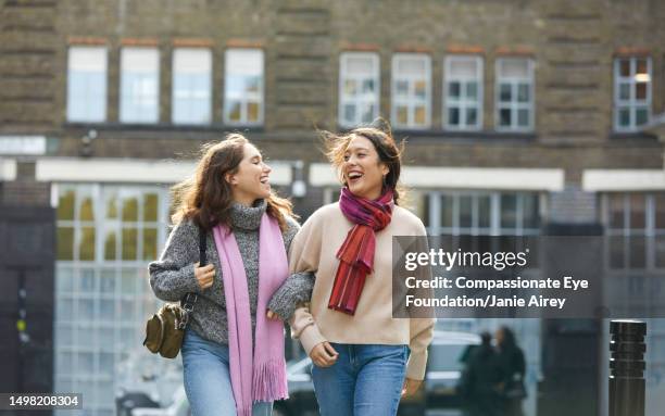 two young women walking on city street - cream colored pants stock pictures, royalty-free photos & images