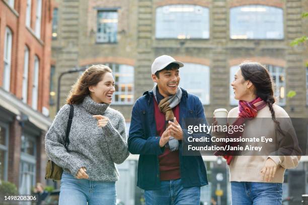 smiling friends on city street - beige trousers stock pictures, royalty-free photos & images
