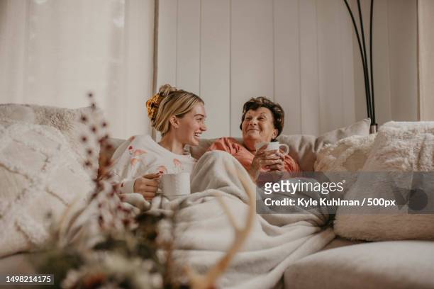 grandma and granddaughter laughing,edwardsburg,michigan,united states,usa - family on couch with mugs stock-fotos und bilder