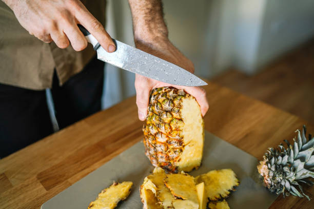portrait of man cutting pineapple on table,home cozy morning breakfast with fruits,spain - ananas comosus stock pictures, royalty-free photos & images