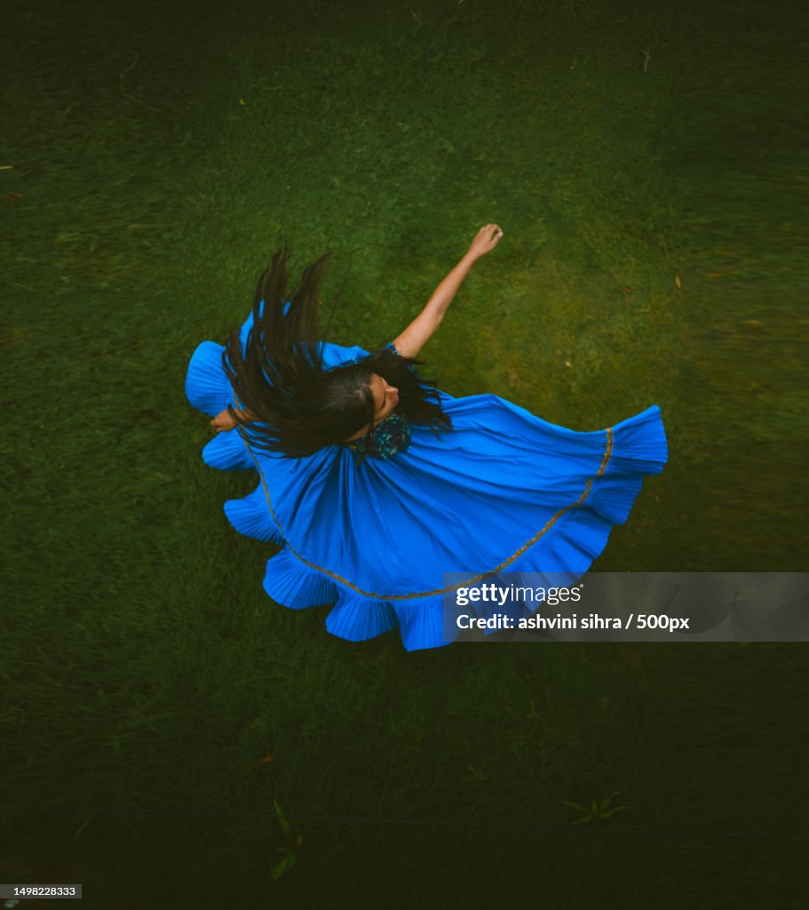 High angle view of woman with blue dress dancing on field,India