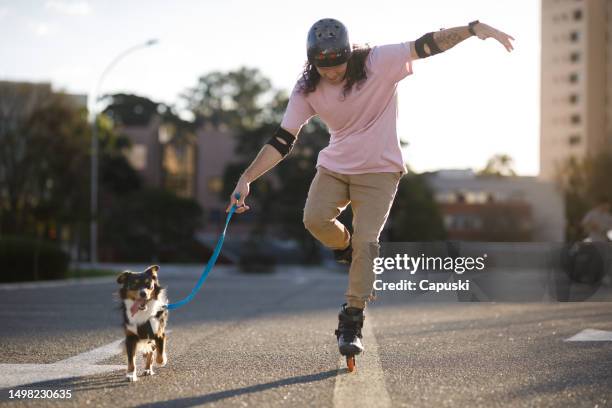 man having fun roller blading with his dog on the street - skaten stockfoto's en -beelden