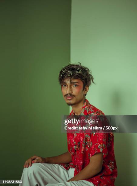 portrait of young man wearing traditional clothing while sitting against green background,india - editorial style stock pictures, royalty-free photos & images