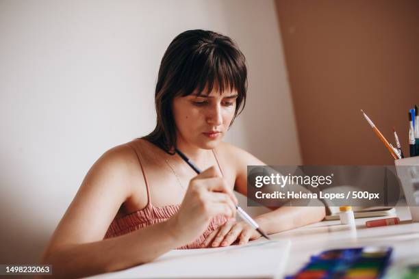 young woman focused on painting paper at table at home,belo horizonte,minas gerais,brazil - aquarela stock pictures, royalty-free photos & images