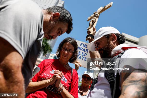 Supporters of former U.S. President Donald Trump pray as outside the Wilkie D. Ferguson Jr. United States Federal Courthouse during his arraignment...