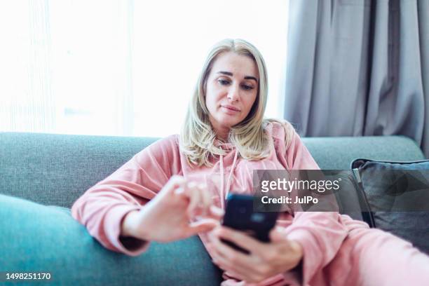 pensive mature adult woman sitting with mobile at home - one woman only 35-40 stock pictures, royalty-free photos & images
