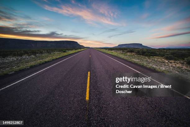 paved road with yellow stripes in big bend national park during sunset - viaje-en-carro fotografías e imágenes de stock