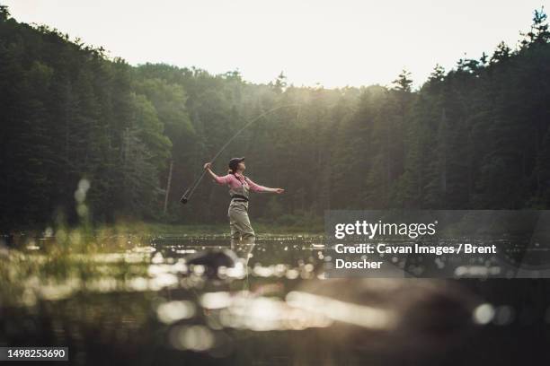 woman angler checking fly rod in nh backcountry lake during afternoon - fly fishing fotografías e imágenes de stock