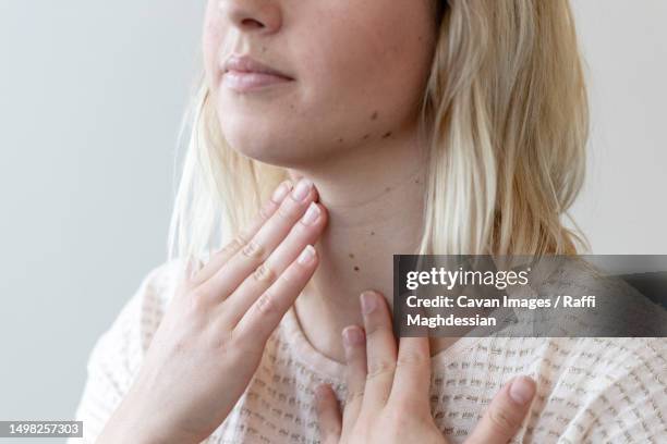 a young woman feels her thyroid gland - thyroid gland stock pictures, royalty-free photos & images