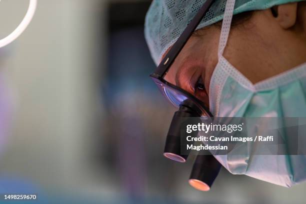 close up view of a heart surgeon wearing his magnifying glasses - herzoperation stock-fotos und bilder