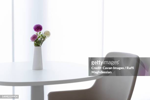 a round table with a vase and a leather chair - round table ストックフォトと画像