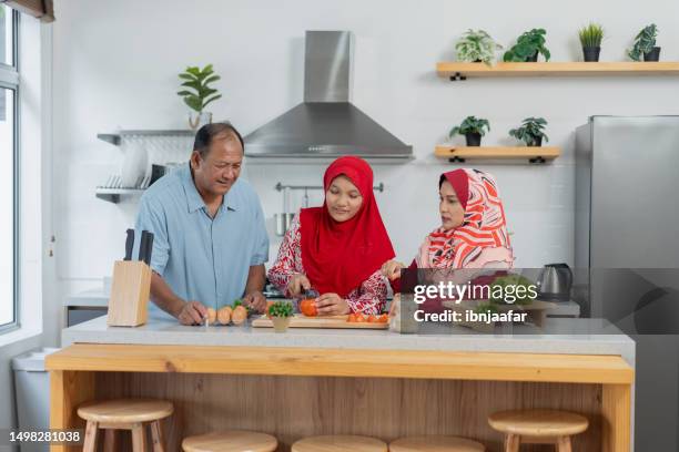 multigenerational family cooking and eating healthy food at home - ibnjaafar stock pictures, royalty-free photos & images