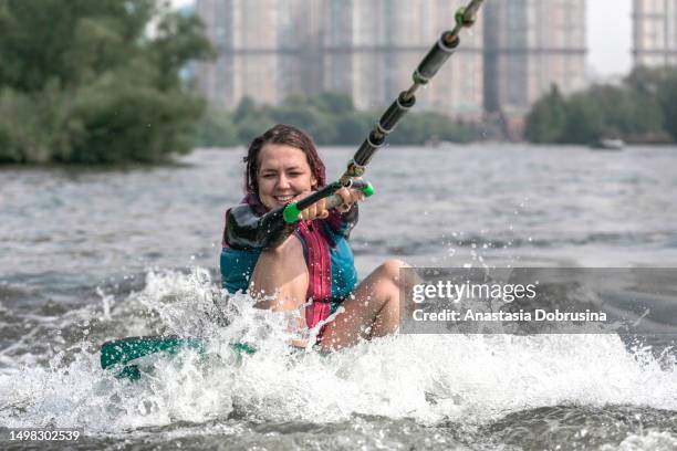 young woman wakesurfing down the river waves - wakesurfing stock pictures, royalty-free photos & images