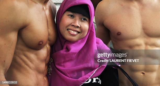 An Indonesian woman poses for photographs with topless male models outside the soon to open Abercrombie & Fitch flagship clothing store in Hong Kong...