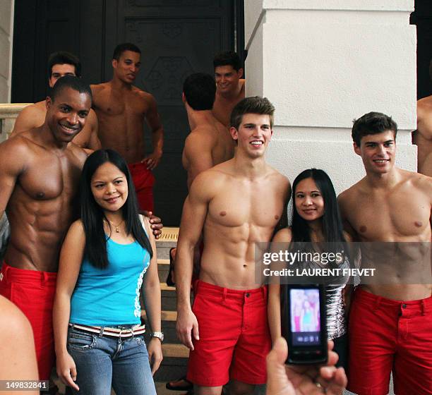 Filipino women pose for photographs with topless male models outside the soon to open Abercrombie & Fitch flagship clothing store in Hong Kong on...
