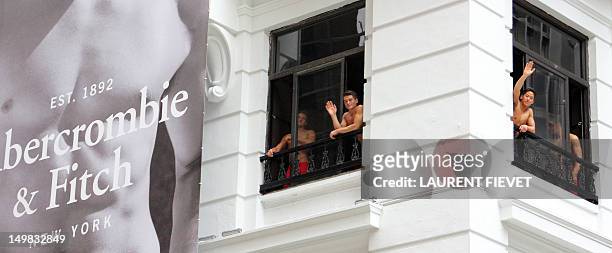Topless male models wave to a crowd of onlookers from the soon to open Abercrombie & Fitch flagship clothing store in Hong Kong on August 5, 2012....
