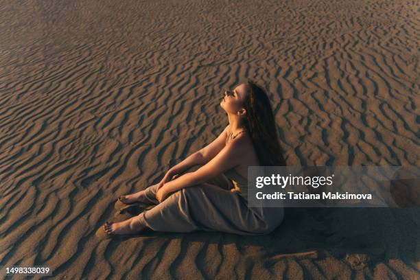 beautiful young ginger woman in desert area on sunset light. - abu dhabi beach stock-fotos und bilder