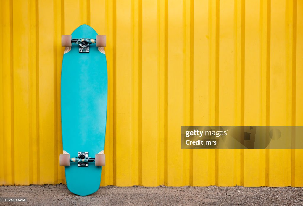 Longboard leaning on yellow wall