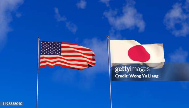usa and japan flags on blue sky - las américas fotografías e imágenes de stock