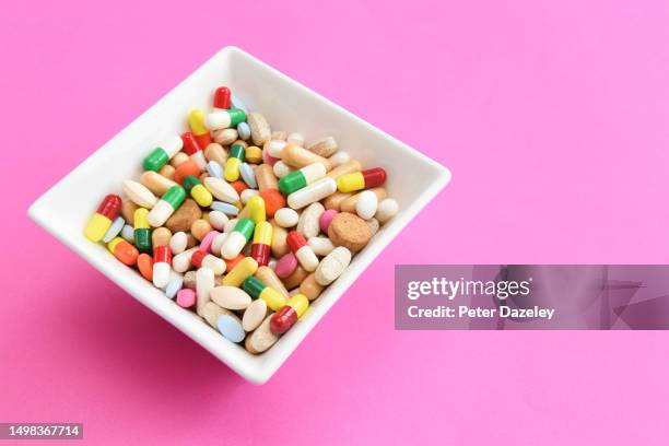 bowl of a mixture of pills on pink background - ibuprofen stock pictures, royalty-free photos & images