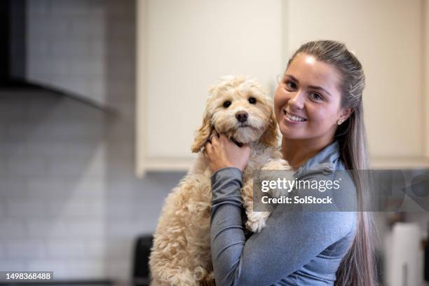 young female adult holding her puppy - day in the life series stock pictures, royalty-free photos & images