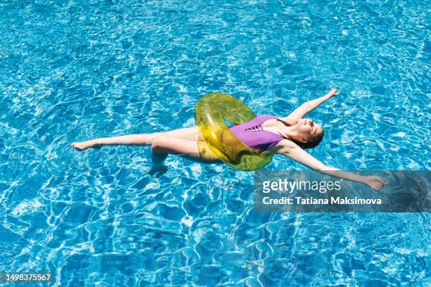 beautiful young woman in blue swimming pool. - floating on water stock pictures, royalty-free photos & images