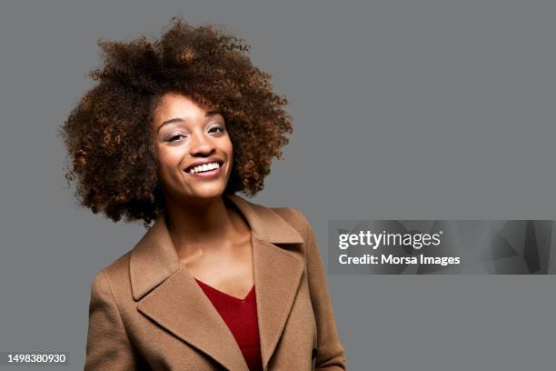 portrait of woman laughing against gray background - black coat stock pictures, royalty-free photos & images