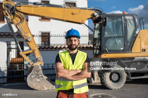 construction worker man portrait outdoors, backhoe bulldozer in background, home renovation - baustelle bagger stock-fotos und bilder