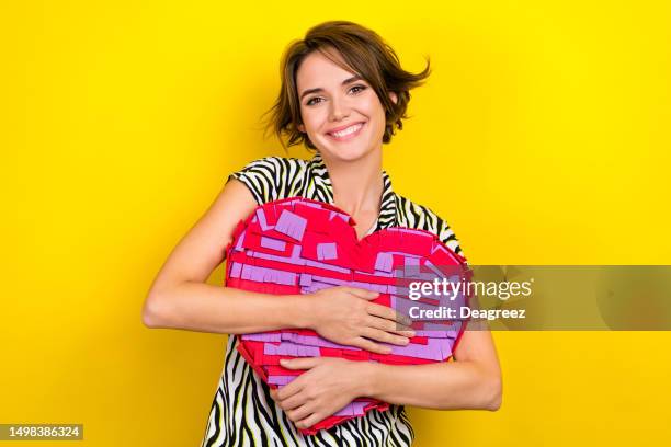 Portrait of gorgeous appreciative woman with short haircut wear striped blouse hugging big heart isolated on yellow color background